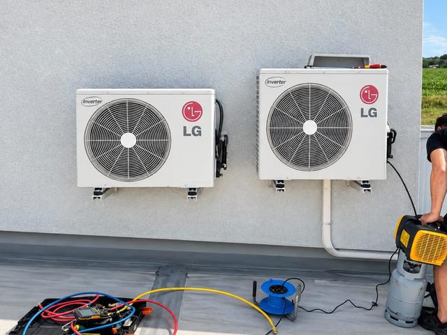 Technik při servisu dvou venkovních jednotek klimatizace LG na fasádě
